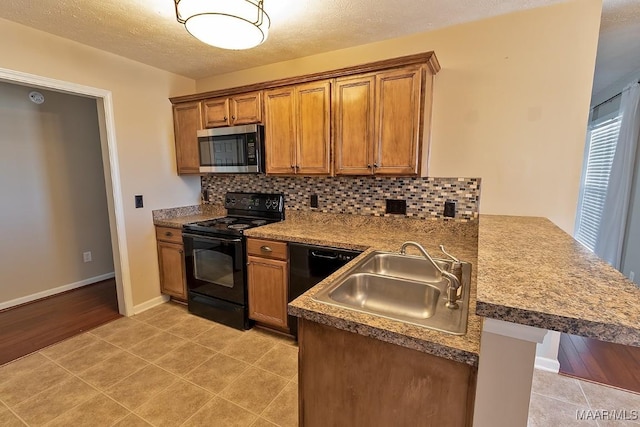 kitchen featuring black appliances, kitchen peninsula, sink, and a kitchen bar