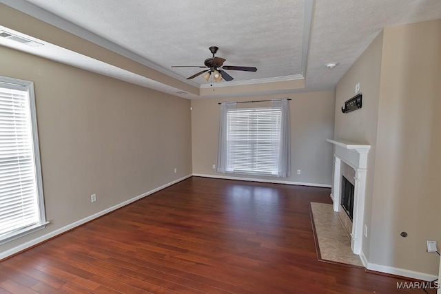 unfurnished living room featuring ceiling fan, a fireplace, a raised ceiling, a textured ceiling, and dark hardwood / wood-style flooring