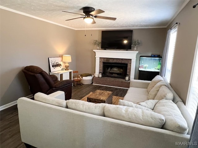 living room with a textured ceiling, dark hardwood / wood-style flooring, a fireplace, ornamental molding, and ceiling fan