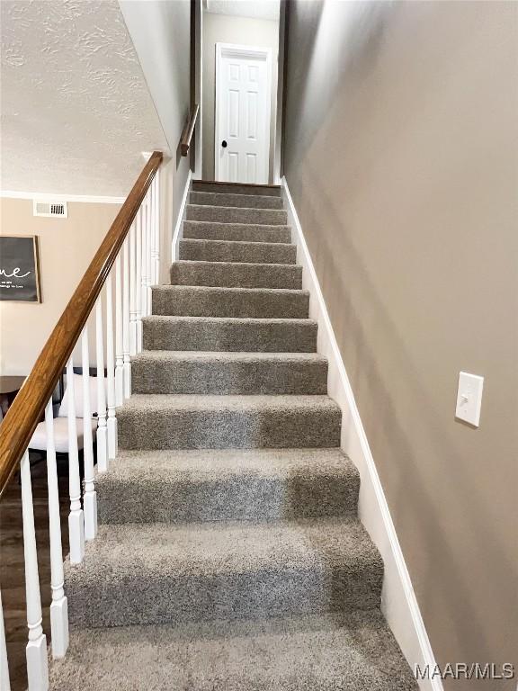 staircase featuring a textured ceiling