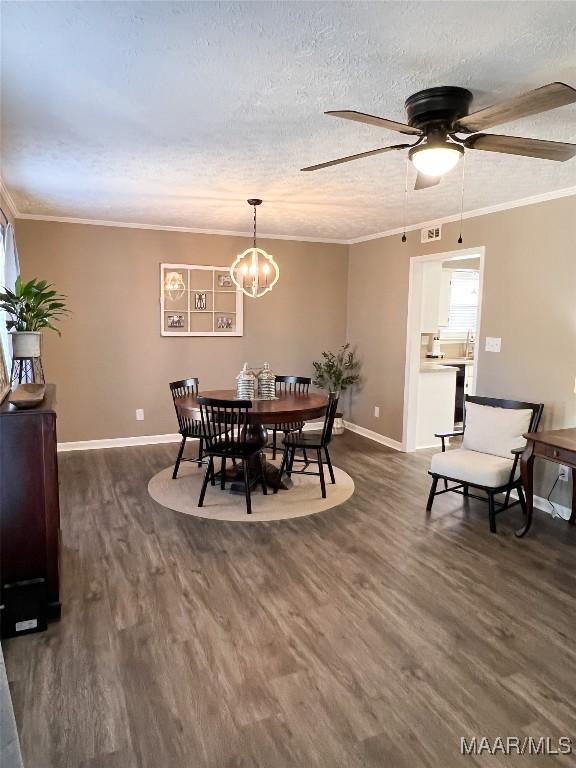 dining area featuring a textured ceiling, dark wood-type flooring, crown molding, and ceiling fan with notable chandelier