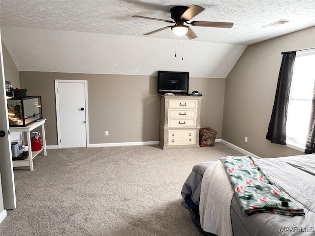 bedroom featuring a textured ceiling, ceiling fan, vaulted ceiling, and light colored carpet