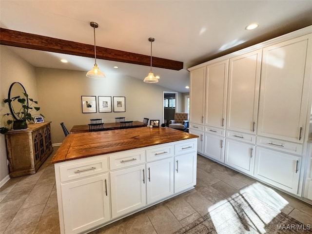 kitchen featuring a kitchen island, pendant lighting, butcher block countertops, vaulted ceiling with beams, and white cabinets