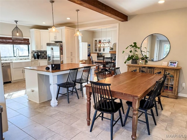 dining area with light tile patterned floors, sink, and beamed ceiling