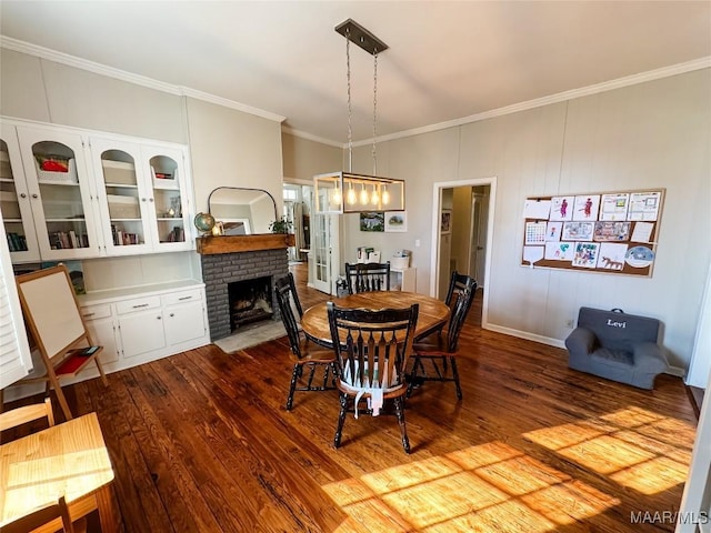 dining space featuring wood-type flooring, a brick fireplace, and crown molding