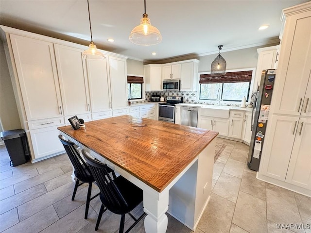 kitchen featuring a healthy amount of sunlight, appliances with stainless steel finishes, pendant lighting, and tasteful backsplash