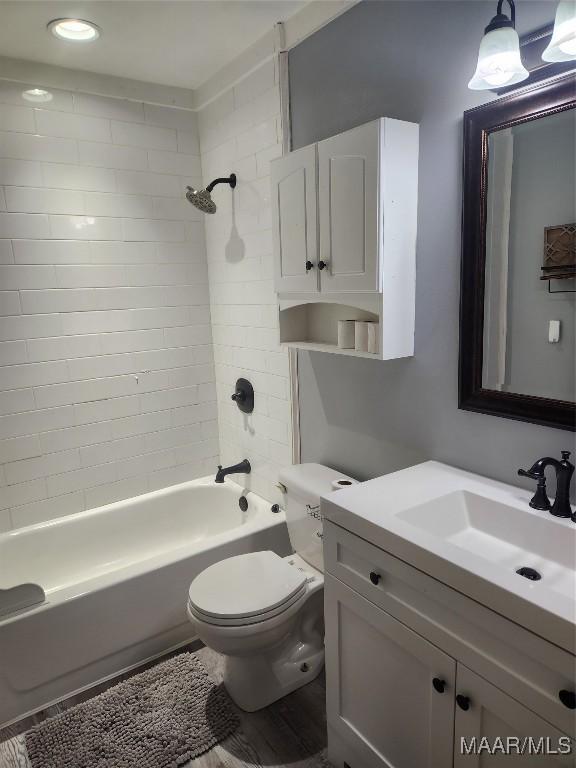 full bathroom with toilet, tiled shower / bath combo, and vanity