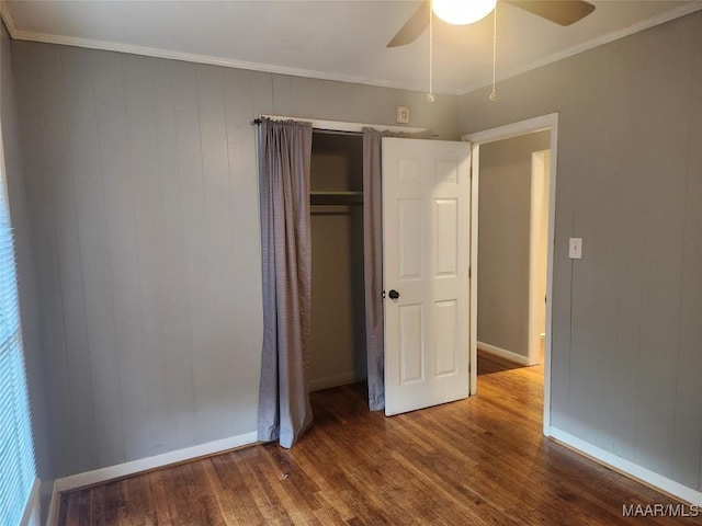 unfurnished bedroom with ceiling fan, wood-type flooring, crown molding, and a closet