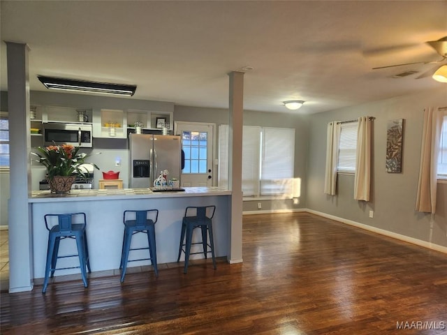 kitchen with a wealth of natural light, dark wood-type flooring, a kitchen breakfast bar, and stainless steel appliances