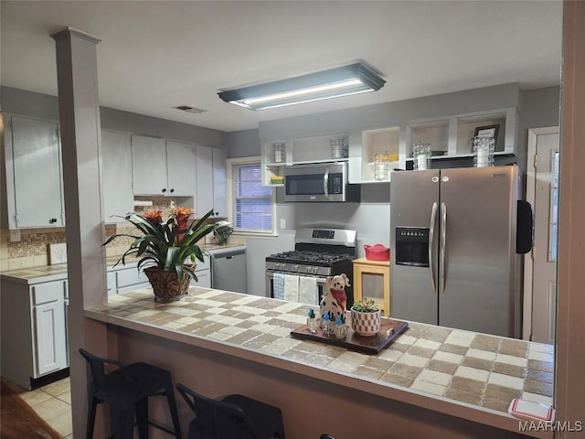 kitchen featuring white cabinets, light tile patterned floors, tile countertops, and stainless steel appliances