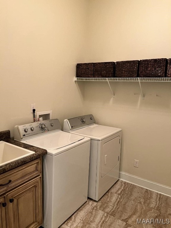 clothes washing area with washer and clothes dryer and cabinets