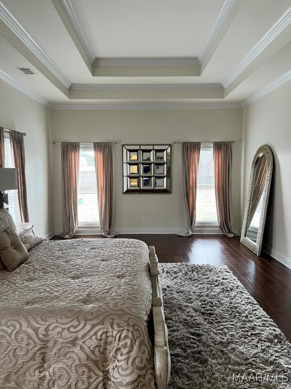 bedroom featuring dark wood-type flooring, ornamental molding, and a tray ceiling