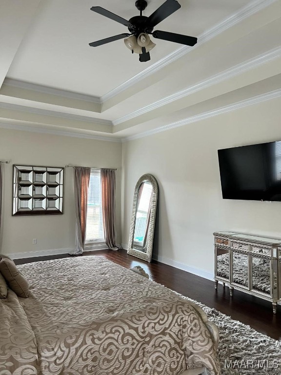 bedroom featuring ceiling fan, a tray ceiling, dark hardwood / wood-style flooring, and ornamental molding