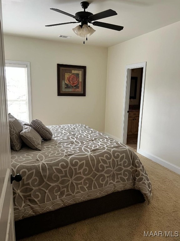 carpeted bedroom featuring ceiling fan and ensuite bath