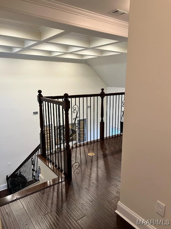 hall with wood-type flooring, ornamental molding, and beamed ceiling