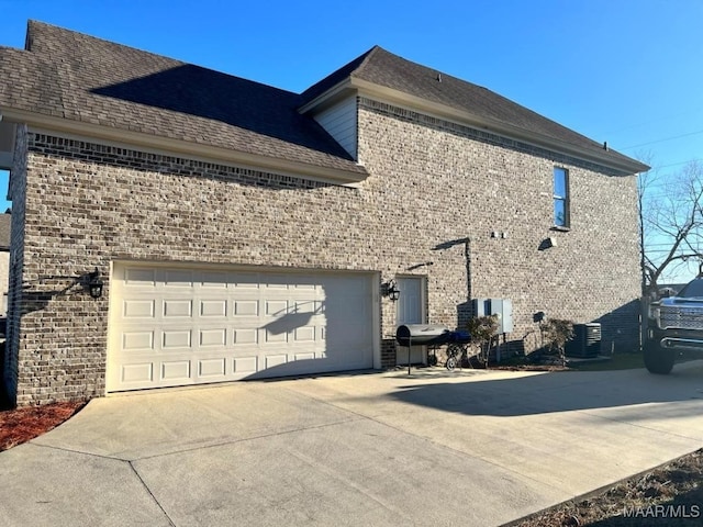 view of side of home with central AC unit and a garage