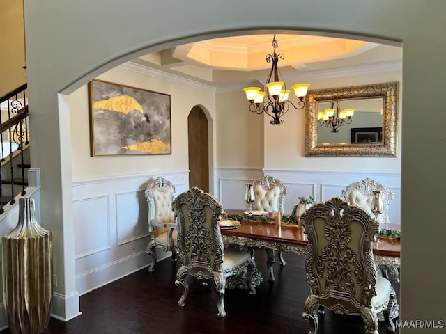 dining space with wood-type flooring, a tray ceiling, an inviting chandelier, and ornamental molding