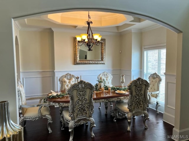 dining area with a chandelier, ornamental molding, wood-type flooring, and a tray ceiling