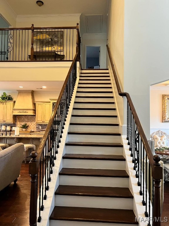 stairs featuring wood-type flooring and crown molding