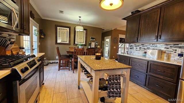 137 Scott Ln, Prattville, AL 36066 - kitchen featuring appliances with stainless steel finishes, decorative backsplash, dark brown cabinets, ornamental molding, and decorative light fixtures
