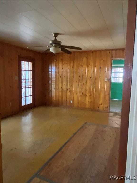 spare room with ceiling fan, a wealth of natural light, and wooden walls