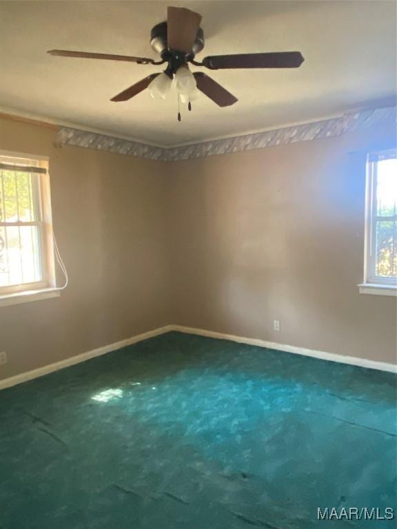 carpeted empty room with ceiling fan and plenty of natural light