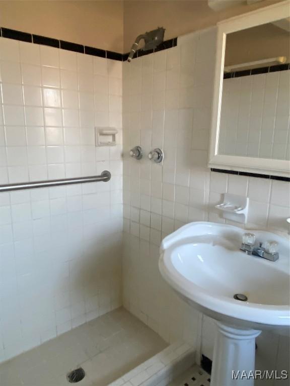 bathroom with a tile shower, tile patterned floors, backsplash, and sink