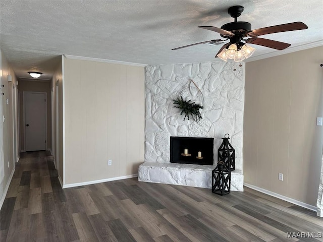 unfurnished living room with crown molding, a stone fireplace, dark wood-type flooring, and a textured ceiling