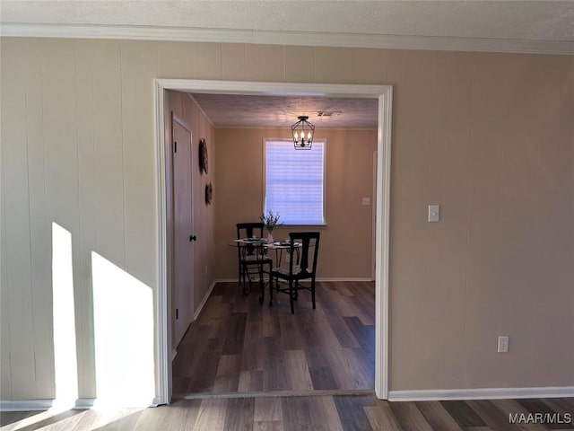 dining room featuring a notable chandelier, dark wood-type flooring, ornamental molding, and a textured ceiling