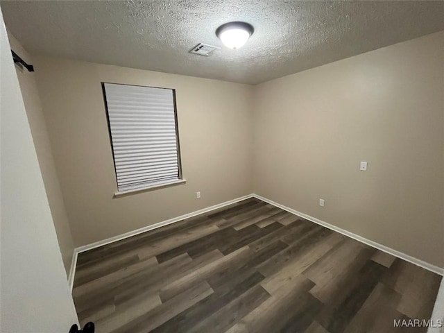 unfurnished room with dark wood-type flooring and a textured ceiling