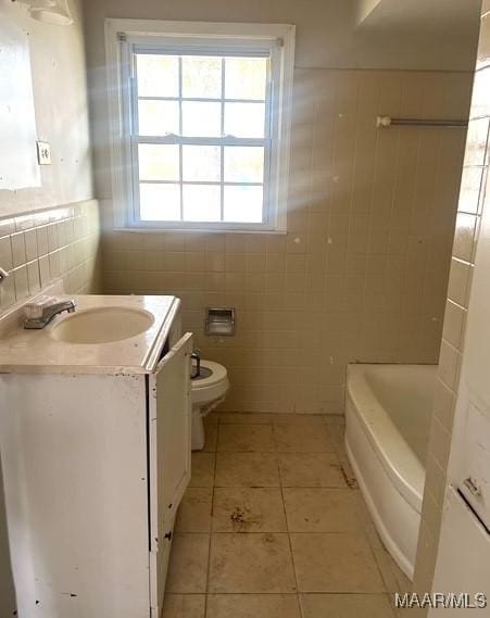 bathroom featuring tile patterned flooring, vanity, tile walls, toilet, and a washtub