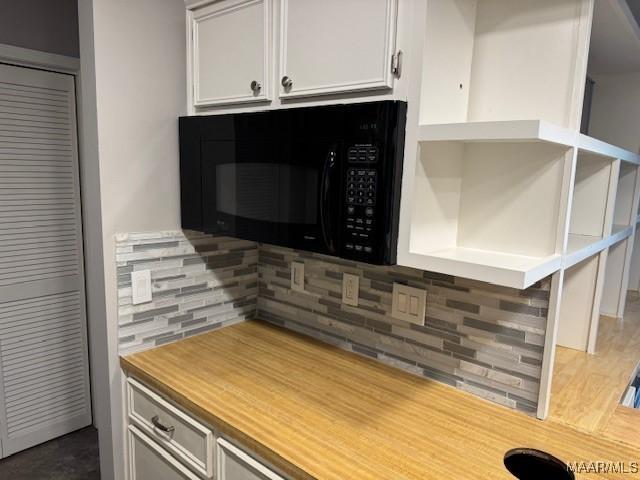 kitchen with tasteful backsplash and white cabinetry