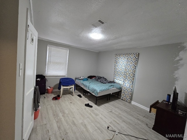 bedroom featuring light hardwood / wood-style floors and a textured ceiling