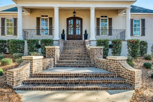 property entrance with covered porch and french doors