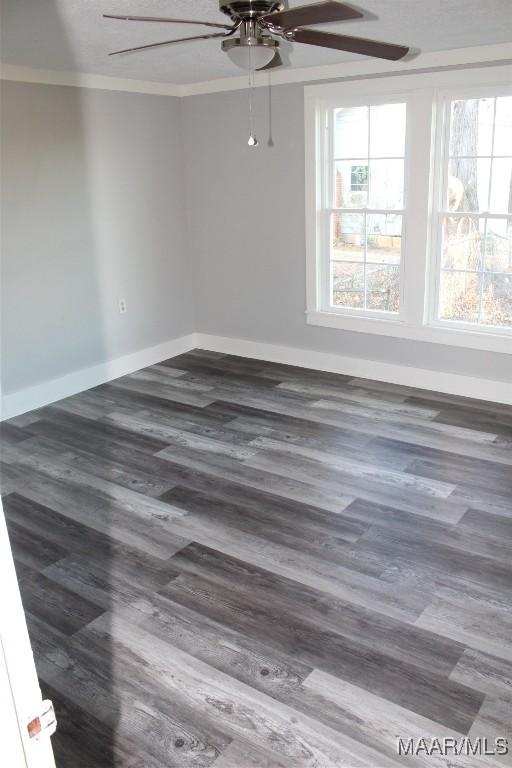 empty room with ceiling fan, dark hardwood / wood-style flooring, and crown molding