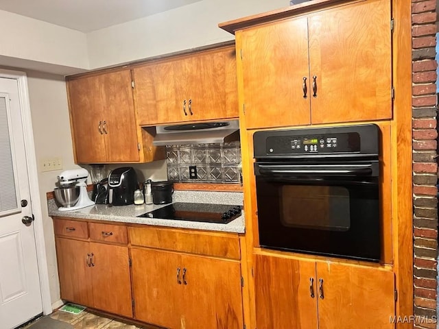 kitchen with black appliances, tasteful backsplash, and range hood