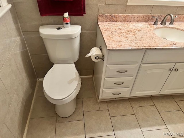 bathroom featuring toilet, tile patterned flooring, tile walls, and vanity