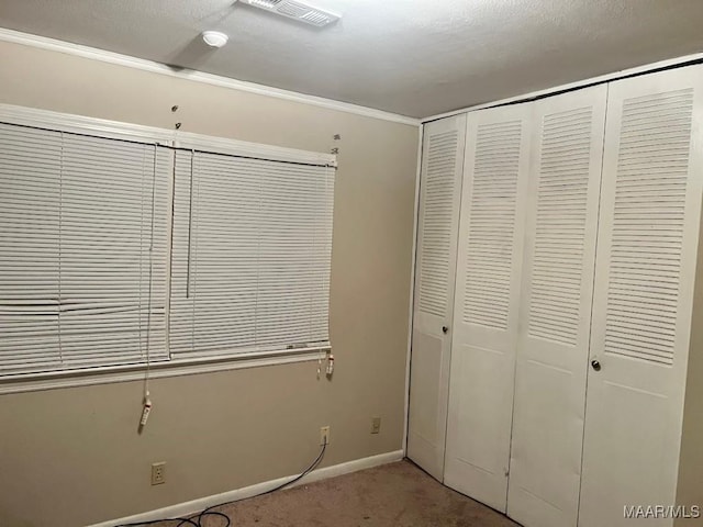 unfurnished bedroom with a closet, carpet, and crown molding