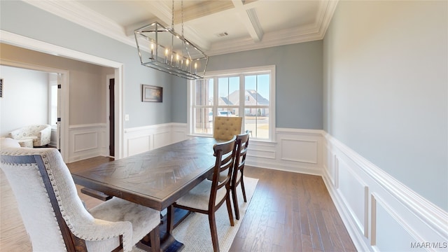 dining area with beamed ceiling, an inviting chandelier, crown molding, coffered ceiling, and hardwood / wood-style flooring