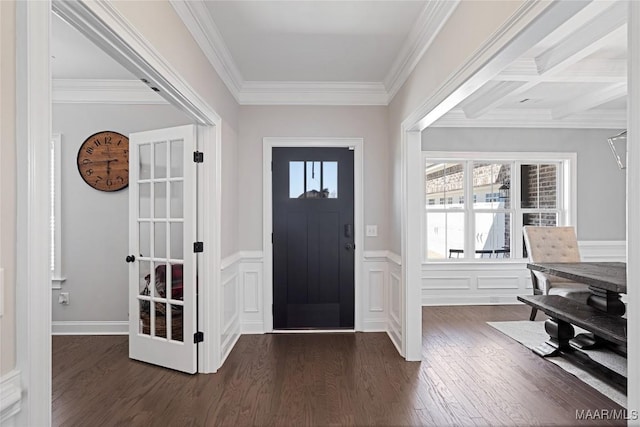 foyer featuring a wainscoted wall, ornamental molding, a decorative wall, and dark wood-type flooring