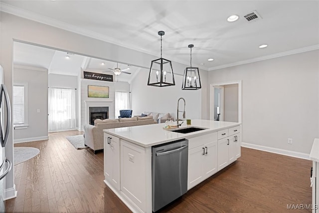 kitchen with stainless steel appliances, dark wood-type flooring, a sink, an island with sink, and a glass covered fireplace