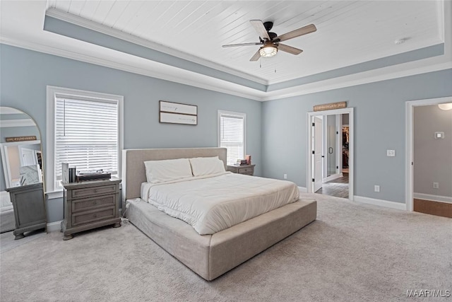 bedroom with ornamental molding, a tray ceiling, light colored carpet, and baseboards