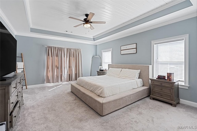 bedroom with a raised ceiling, multiple windows, and light carpet