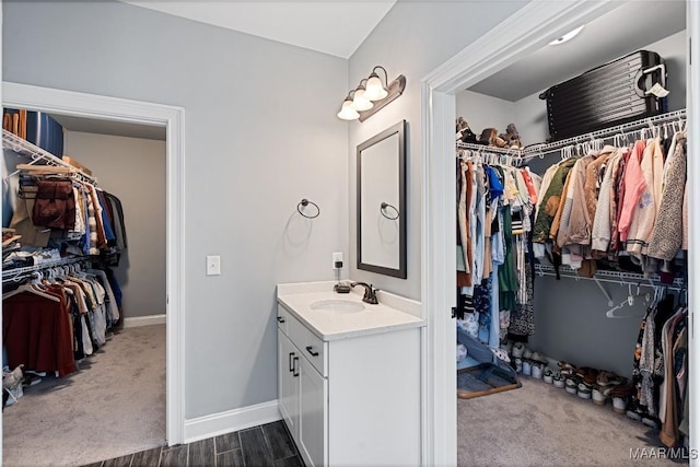 bathroom featuring baseboards, a walk in closet, and vanity