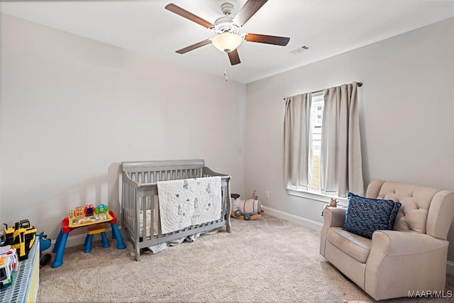 bedroom featuring carpet floors, a ceiling fan, visible vents, baseboards, and a nursery area