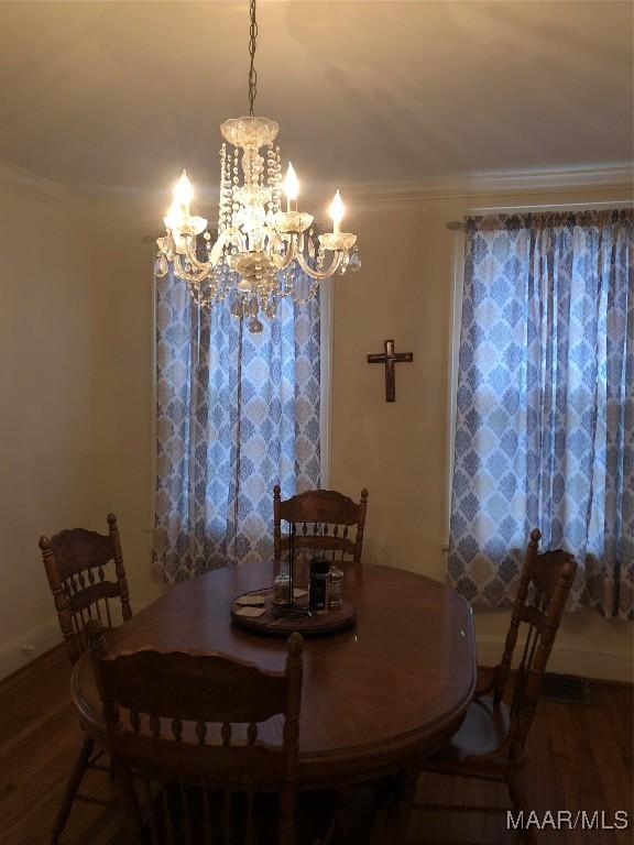 dining room with crown molding, a notable chandelier, and hardwood / wood-style flooring