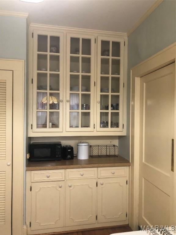 bar with ornamental molding and white cabinets