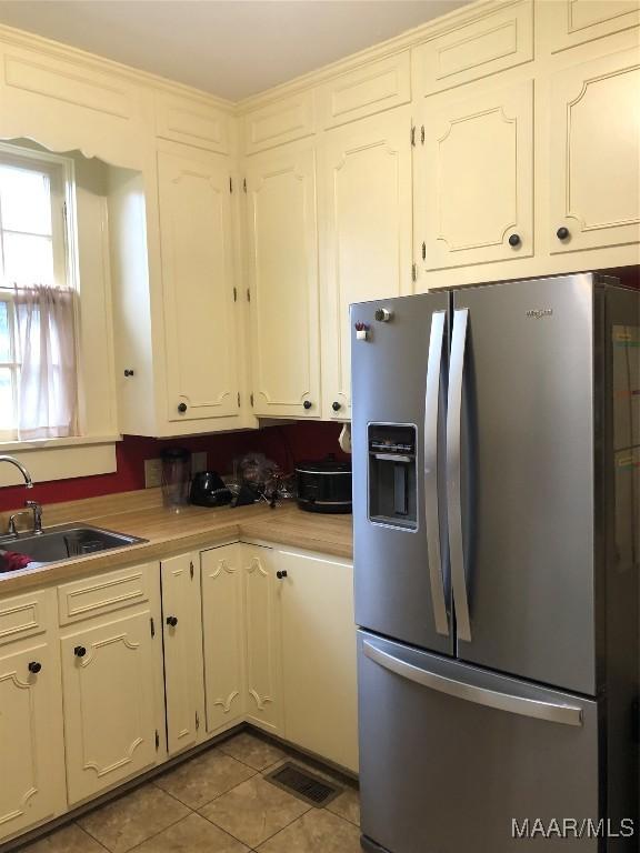 kitchen featuring white cabinets, sink, stainless steel fridge with ice dispenser, and light tile patterned floors