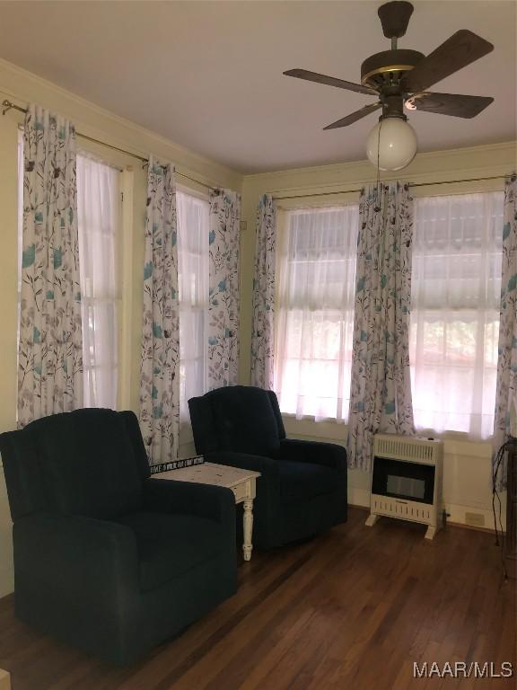 living area featuring hardwood / wood-style flooring, heating unit, and ceiling fan