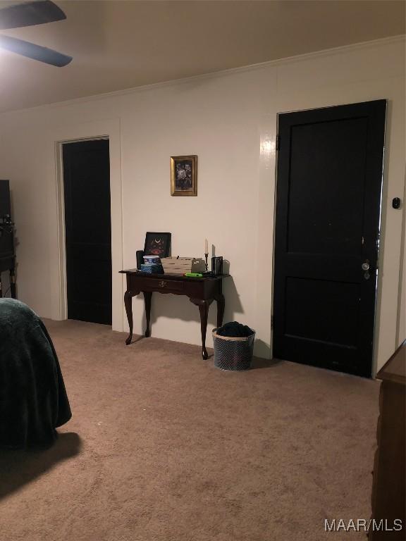 carpeted bedroom featuring crown molding and ceiling fan